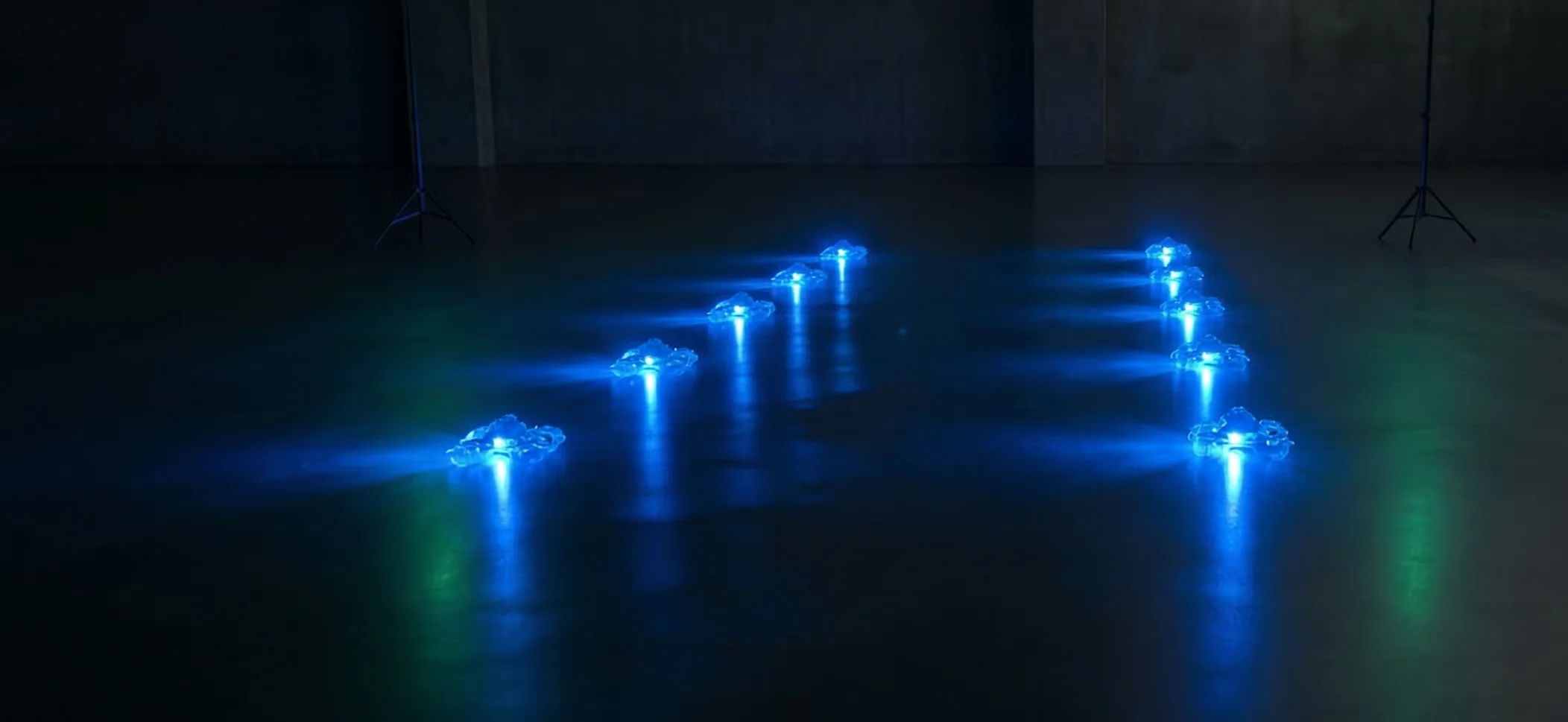 Un grupo de 10 drones con luz azul sobre el suelo antes de empezar el espectáculo indoor